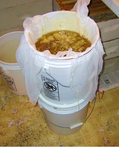 On the right, using the double bucket strainer to strain honey.
